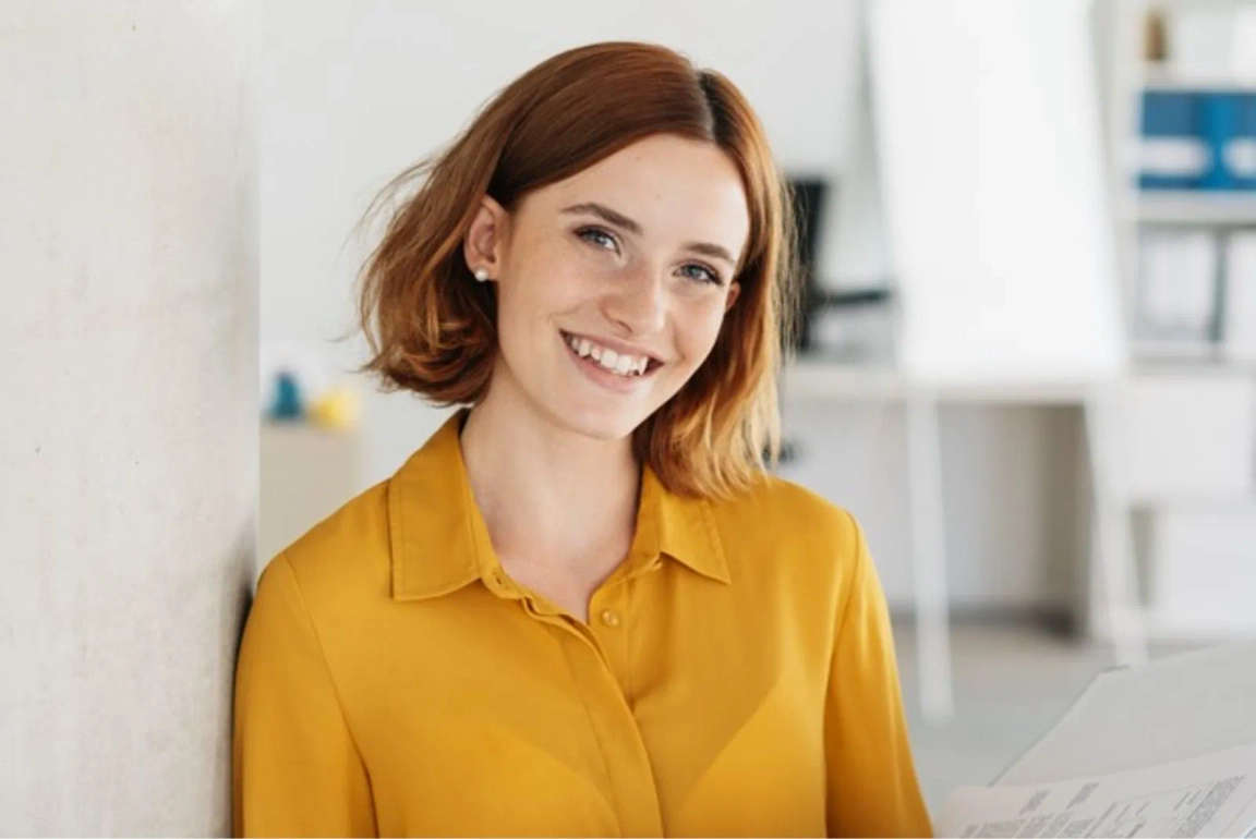 Woman smiling leaning against a wall